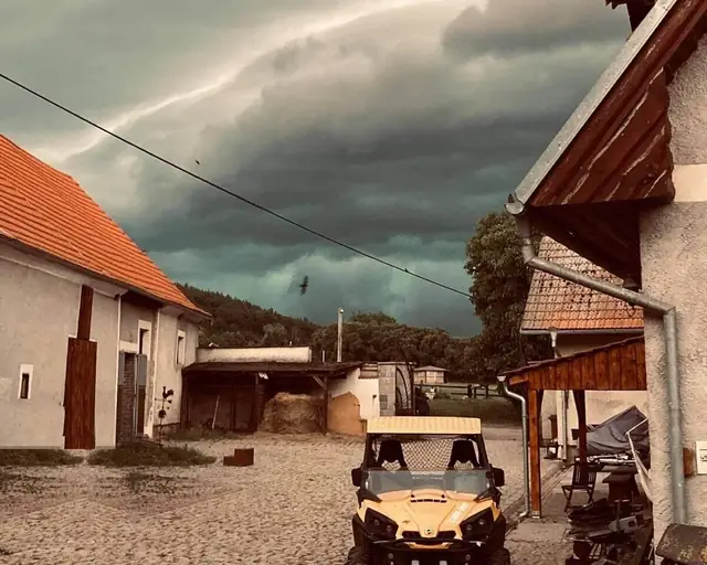 Dvůr areálu se stájemi a bouřková obloha nad údolím