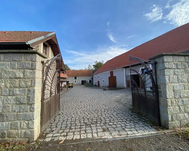 Vjezd do areálu bývalého mlýna — kovaná brána a dlážděný dvůr